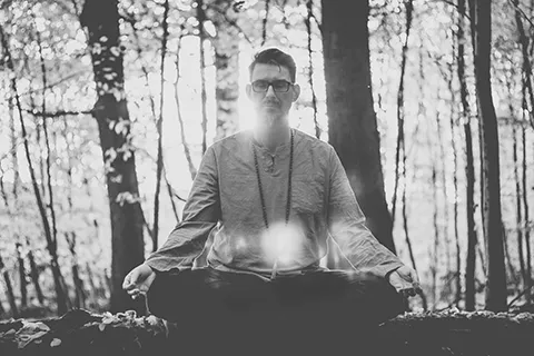 Micha Madhava meditiert sitzend im Wald