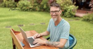 Madhava sitzt mit Laptop am Schreibtisch