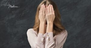 Frau hält sich beide Hände vor das Gesicht