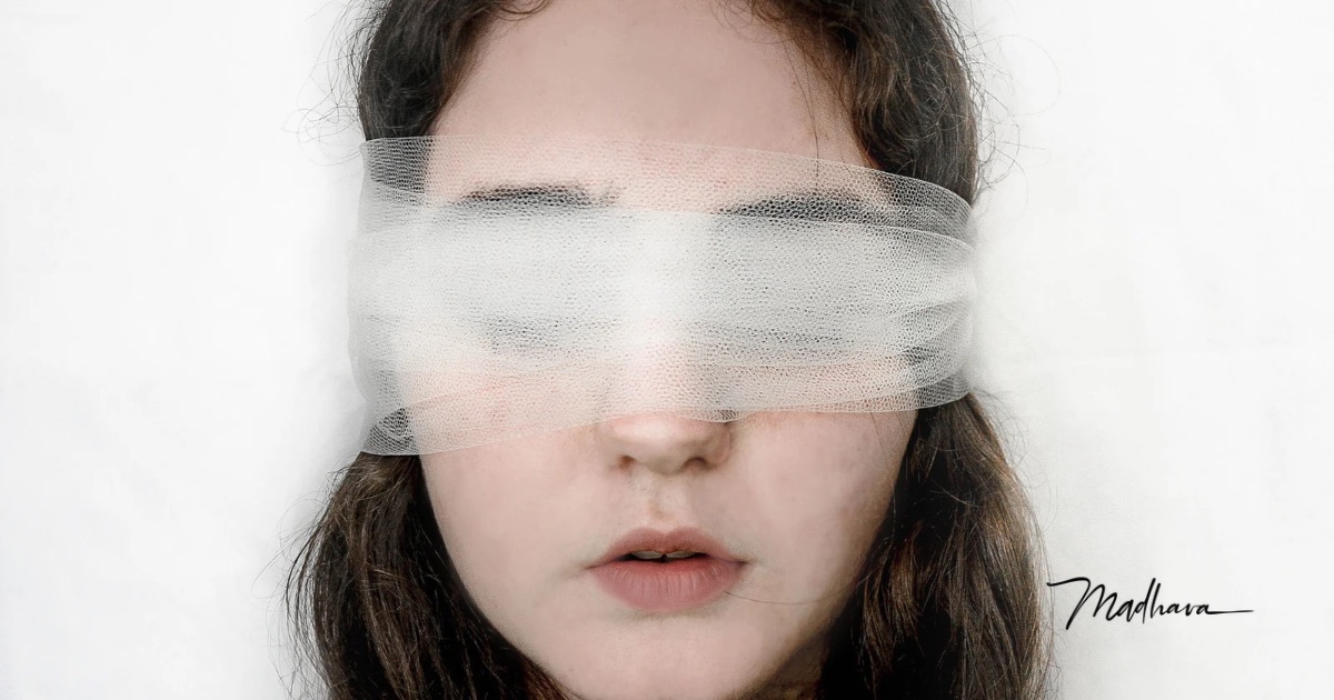 Junge Frau mit langen braunen Haaren, die Augen mit einem durchscheinenden weißen Tüllband verbunden, die Lippen leicht geöffnet, vor weißem Hintergrund, Sinnbild für verordnetes Vertrauen und aufgegebene Wahrnehmung.